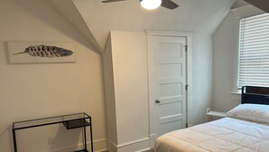 A bedroom with a bed, a nightstand, a ceiling fan, a door, and a wall-mounted artwork. - Main Stay on Market Unit 3 -Healthcare and Military Friendly (Mascoutah)