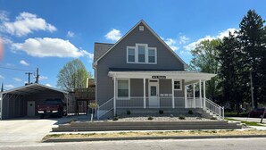A two-story house with a porch, a garage, and a small driveway. - Main Stay on Market Unit 3 -Healthcare and Military Friendly (Mascoutah)