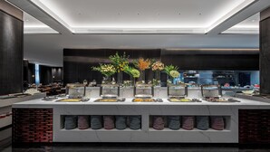 Un buffet moderne, avec plusieurs présentoirs de nourriture, une composition florale décorative au centre et un design élégant et contemporain.