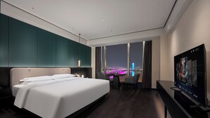 Une chambre d’hôtel moderne avec un grand lit, un bureau et une télévision.
