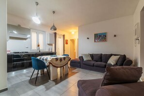 A modern living room with a sofa and a dining area with a table and chairs.