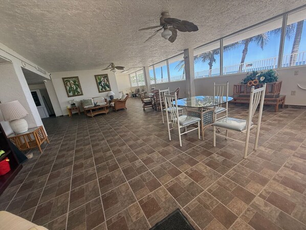 A spacious living area with a large dining table, chairs, and a ceiling fan.