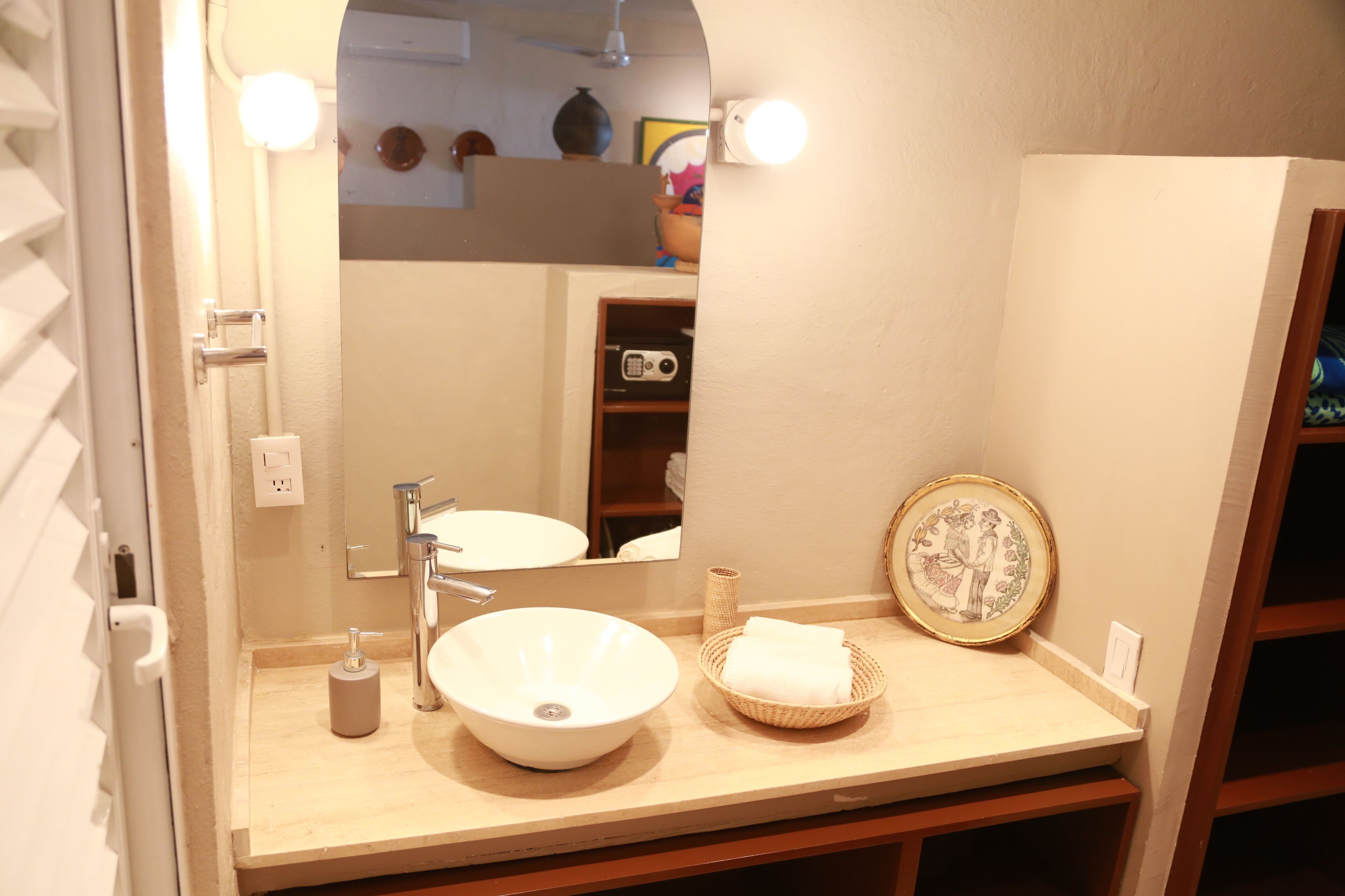 A bathroom with a white sink, a mirror, and a towel basket.