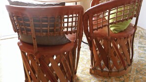 A dining area with a round table, two wicker chairs, a fruit plate, and a hanging light fixture. - Las Cazules - Casa cerca de playa (Puerto Vallarta)