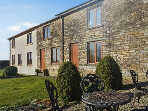 A stone building with multiple windows and doors, a lawn, and outdoor furniture. - The Cottage at Peers Clough Farm (Rossendale, near Clitheroe and the Ribble Valley)