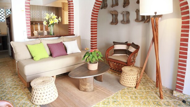 Una sala de estar acogedora con un sofá, sillones, una mesa de centro y una lámpara de pie.