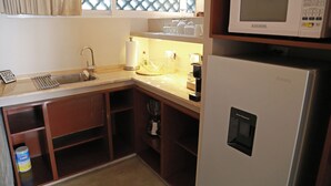 Una cocina compacta con lavamanos, microondas y refrigerador.