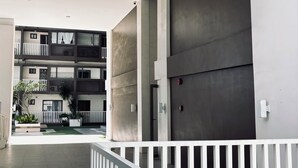 A modern building with a flat roof, a balcony with white railings, and a gated entrance.