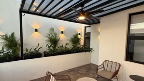 A covered outdoor seating area with wicker furniture, potted plants, and a ceiling fan. - Apartment with Private Rooftop. Start your adventure here at Zefira - 2BR. (Mérida)