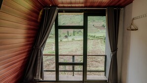 A room with a large window, wooden walls, and a metal gate leading outside. - Dieng Ceria By Travelink (Dieng Kulon)