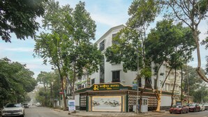 A hotel with a prominent sign, a landscaped entrance, and a street view. - Romeo Hotel Linh Dam 1 - by BAY LUXURY (Hanoi)