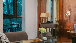 A hotel room with a sofa, a small table with a cup, a vase with flowers, and a lamp. - Romeo Hotel Linh Dam 1 - by BAY LUXURY (Hanoi)