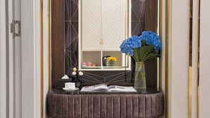 A vanity area with a mirror, a book, a cup, and a vase with flowers. - Romeo Hotel Linh Dam 1 - by BAY LUXURY (Hanoi)