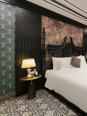 A hotel room with a bed, a nightstand with a lamp, a decorative wall, and patterned flooring. - Romeo Hotel Linh Dam 1 - by BAY LUXURY (Hanoi)