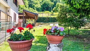 A garden with potted plants and a building with a covered patio. - Nel Castagneto by Interhome (Varenna)