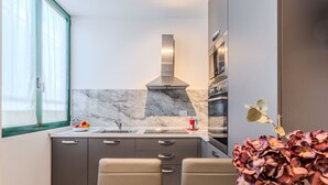 A modern kitchen with a marble backsplash, stainless steel appliances, and a dining area with two chairs.