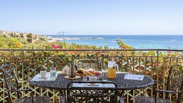 A table set with a pitcher, cups, and a basket of fruit, overlooking a coastal view. - Cicladi Paros by Interhome (Santa Flavia)