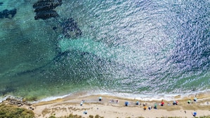 An aerial view of a beach with clear turquoise waters, sandy shore, and dense green vegetation in the foreground. - Cicladi Paros by Interhome (Santa Flavia)