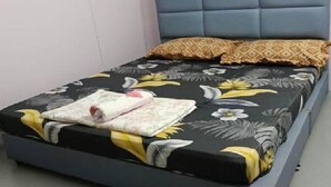 A bed with a floral bedspread, a blue upholstered headboard, and two wall decorations. - Homestay Budget Alor Setar (Jitra)