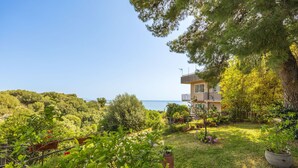 A two-story building with a balcony overlooking a lush garden and a clear view of the sea. - Cicladi Anafi by Interhome (Santa Flavia)
