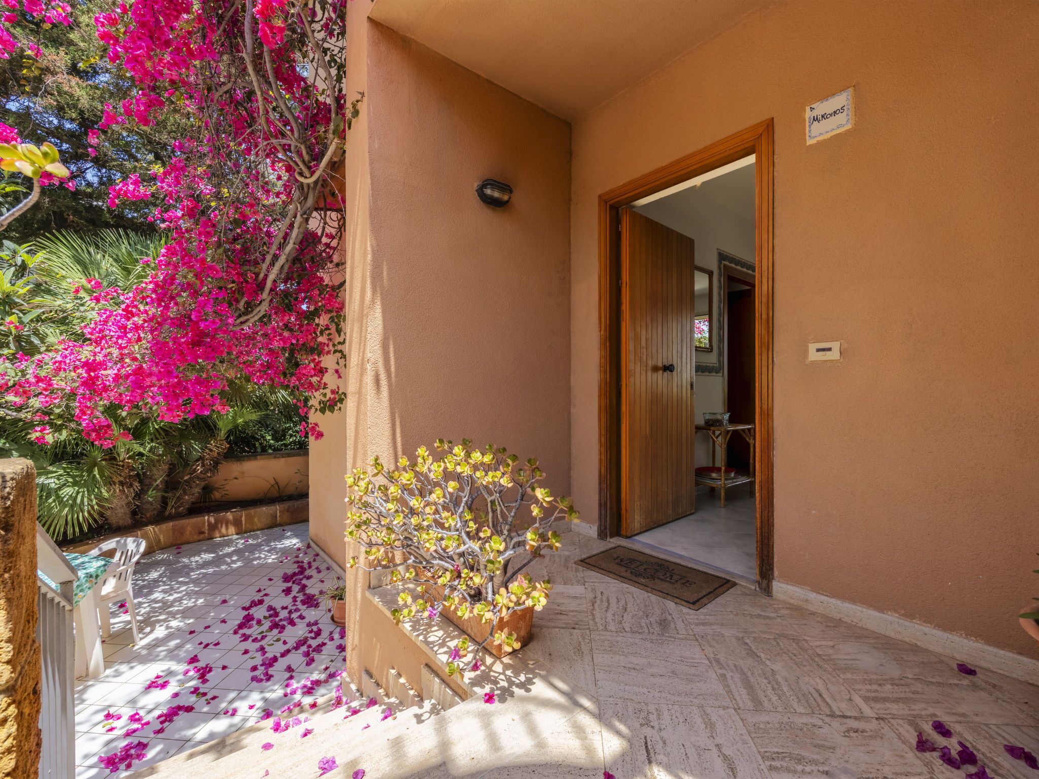 A hotel entrance with a beige wall, a wooden door, and a sign.