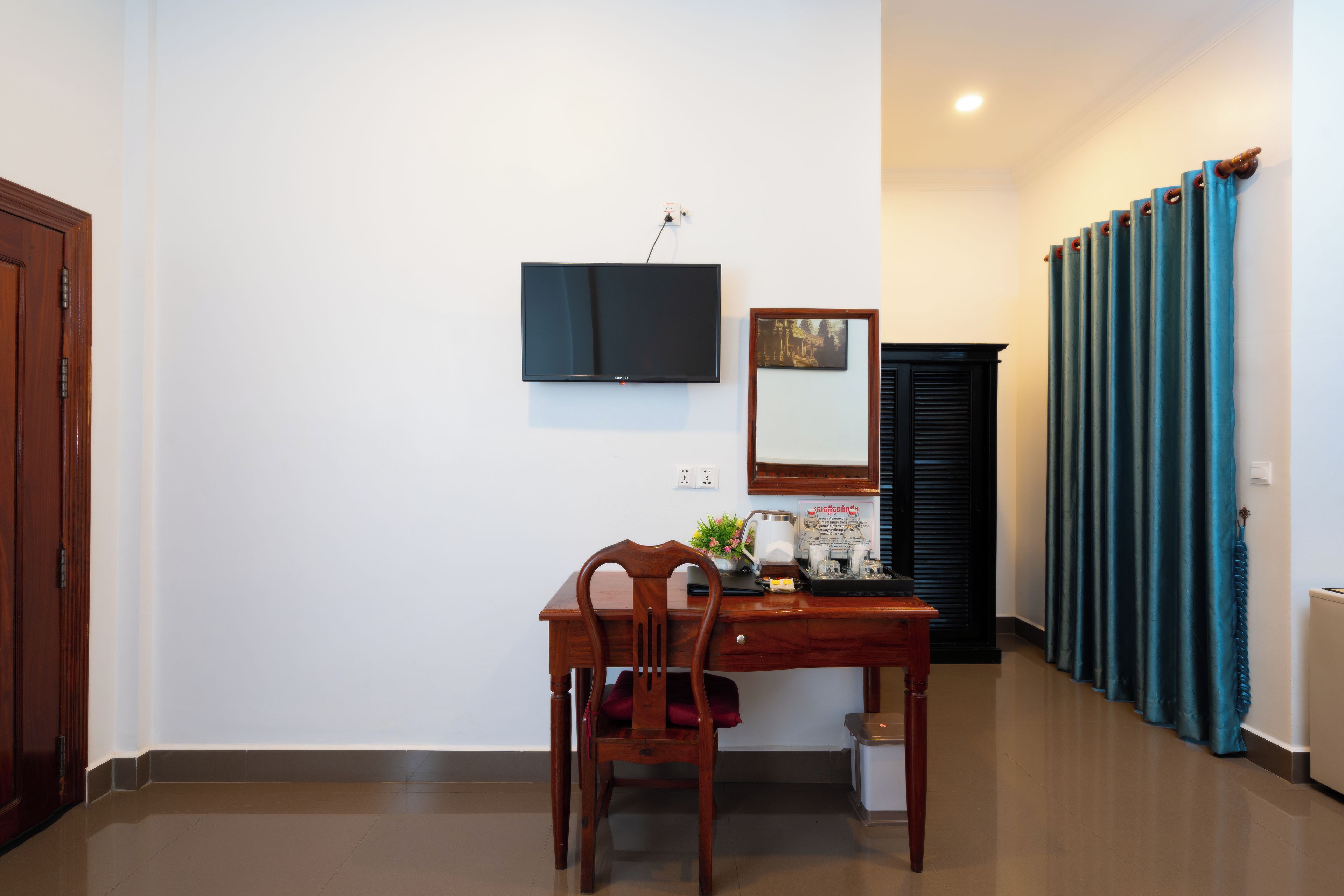 Une chambre d’hôtel avec un bureau en bois, une chaise, un téléviseur fixé au mur, une fenêtre donnant sur un paysage agréable et une porte.