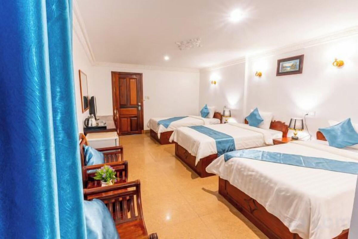 Une chambre d’hôtel avec trois lits, un bureau et une chaise.