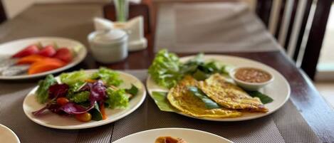 A dining table with plates of food, including pancakes and a salad.