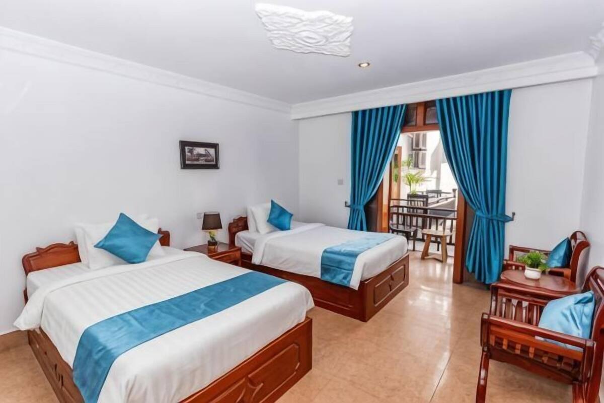 A hotel room with two beds, a desk, and a chair.