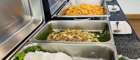 Un bufé con diversas opciones de comida, como fideos, arroz frito y ensaladas.