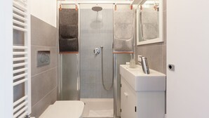Et lille badeværelse med bruser, toilet og håndvask.