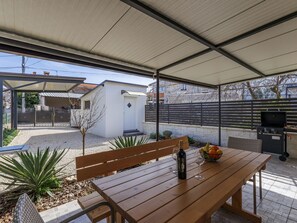 Enjoy al fresco dining in this outdoor space with a table, bench, and grill.
