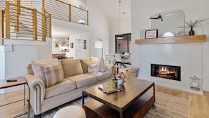 Un salon moderne avec un canapé, une table basse, une cheminée et un escalier menant à un niveau supérieur.