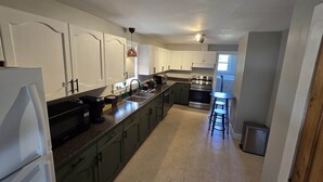 A kitchen with green cabinets, a stainless steel oven, a sink, and a bar stool. - Scenic Shelburne home. Central location close to Shelburne Harbour. (Shelburne)