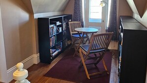 A loft-style room with a wooden floor, a dining table with chairs, a bookshelf, and a black cabinet. - Scenic Shelburne home. Central location close to Shelburne Harbour. (Shelburne)