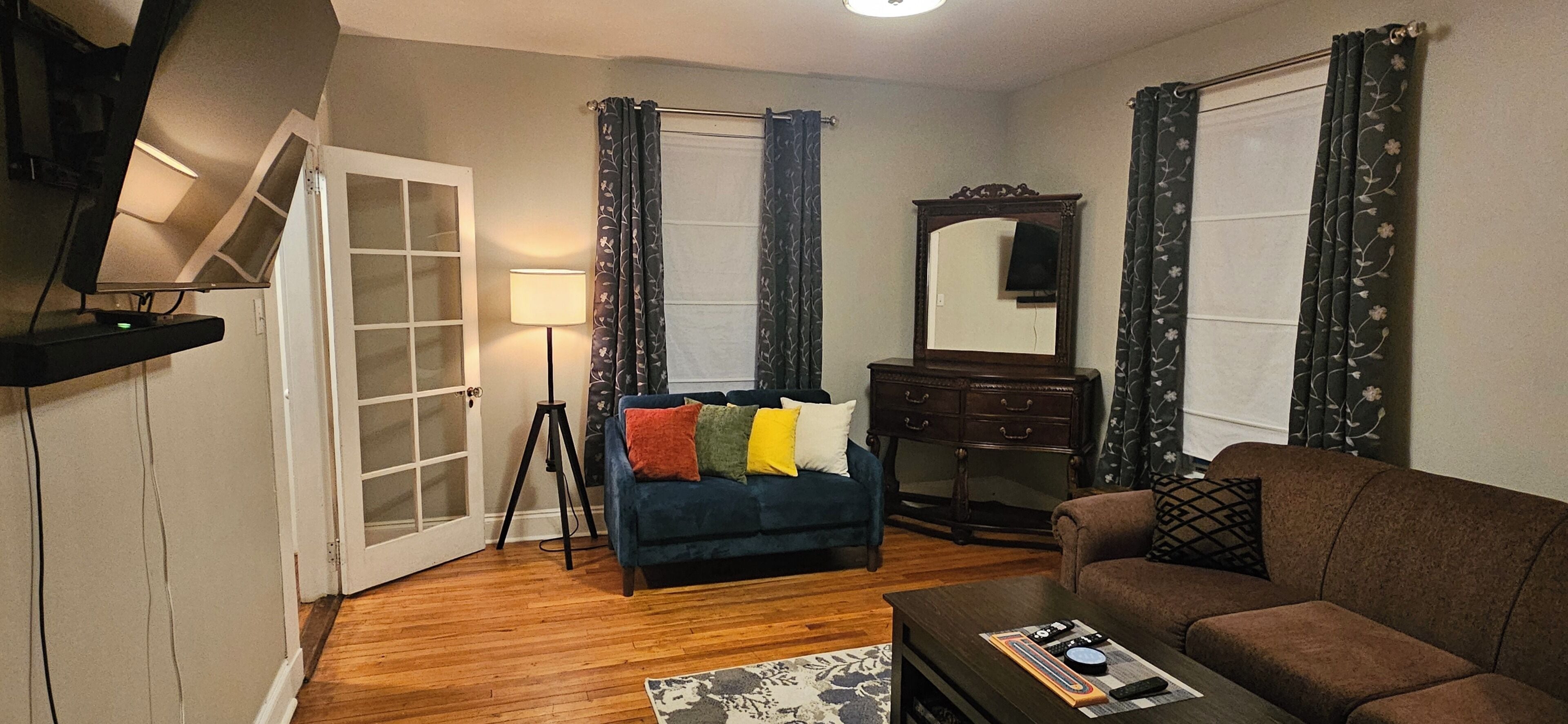 A living room with a blue sofa, a brown sofa, a wooden coffee table, a floor lamp, and a mirror.