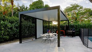An outdoor patio with a covered seating area, a grill, and a pool. - Bonita Ranch (Miami Shores)