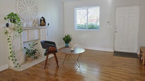 A room with a wooden floor, a fireplace, a round table, and a window with blinds. - Bonita Ranch (Miami Shores)