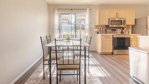 A modern kitchen with wooden cabinets, stainless steel appliances, and a dining area with a table and chairs. - Quiet Comfort-Parking & Patio • WiFi • WD (Austin)