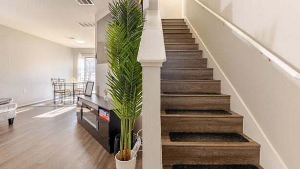 A modern living room with a staircase, a dining area, and a large potted plant. - Quiet Comfort-Parking & Patio • WiFi • WD (Austin)