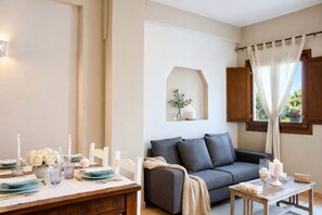 A dining area with a table set for four, a sofa, and a window with curtains. - Dimora Ametista, Baja Sardinia, Italy (Baja Sardinia)