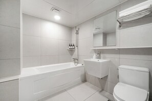 A modern bathroom with a bathtub, a sink, and a toilet. - Haydn Hotel (Busan)