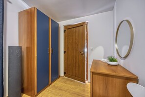Um corredor com um guarda-roupa de madeira, um guarda-roupa azul e uma secretária de madeira com espelho.