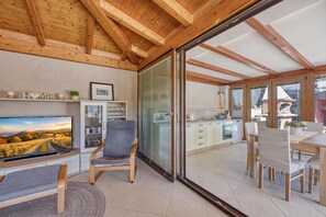 A modern interior with a TV, seating, kitchen, and large sliding glass doors.