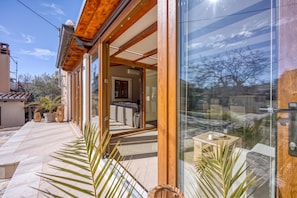 A modern house with a glass door leading to a living area with a sofa and a dining table.