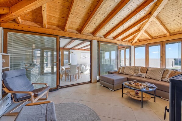 A spacious living area with a wooden ceiling, a sofa, a coffee table, and a chair.