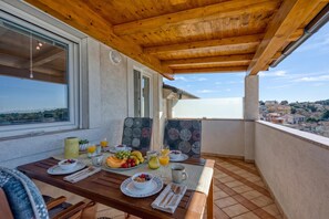 An outdoor dining area with a wooden table set for breakfast, including fruits, bread, and beverages. - Apt Jakara 3 - Sea View Balcony, Vinkuran, Croatia (Vinkuran)