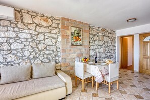 A dining area with a stone wall, a sofa, and a table set for two.