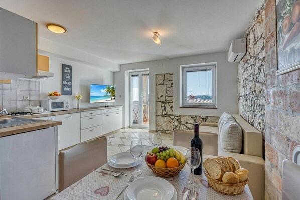 A modern kitchen with a dining area, stone wall, and a TV.