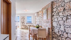 Un coin repas avec un mur en pierre, une table avec des chaises et une vue par la fenêtre.
